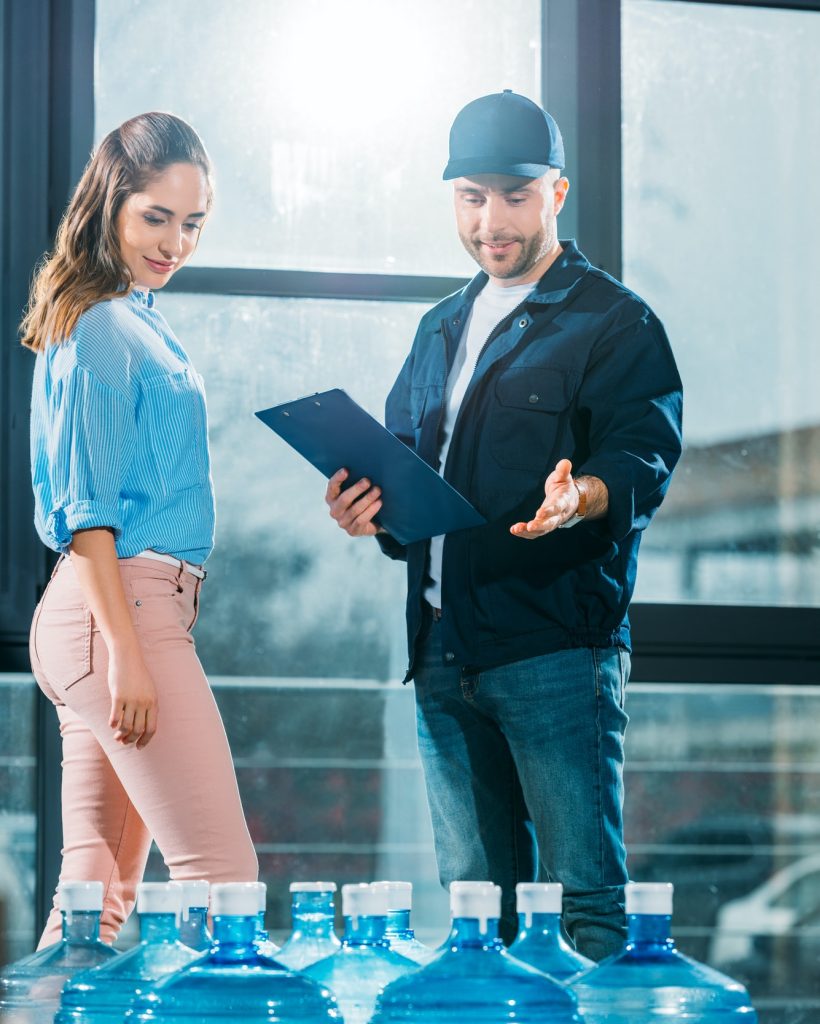courier-with-clipboard-and-woman-looking-at-delivered-water-bottles.jpg courier-with-clipboard-and-woman-looking-at-delivered-water-bottles.jpg